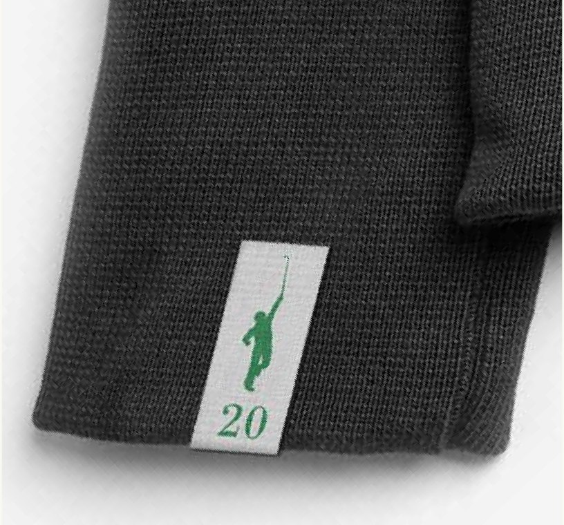 A stitched vintage white woven brand label inside a charcoal performance polo.
